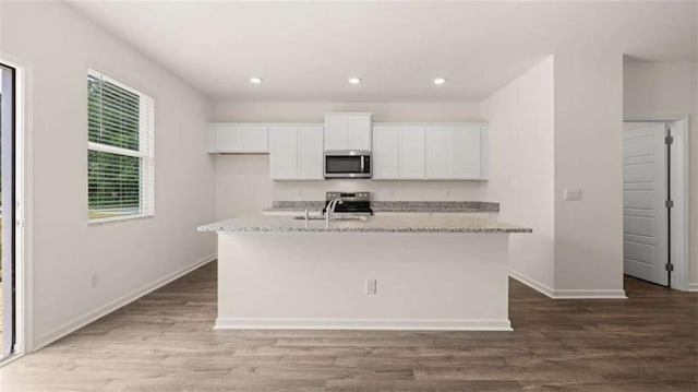 kitchen with white cabinets, stainless steel appliances, dark hardwood / wood-style floors, and a center island with sink