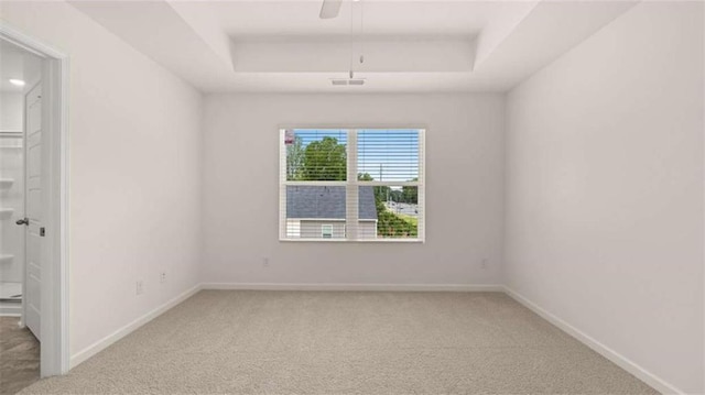 empty room with carpet, a raised ceiling, and ceiling fan