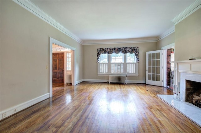 unfurnished living room with ornamental molding, a fireplace, radiator, and hardwood / wood-style floors