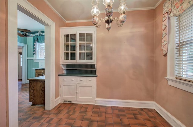 unfurnished dining area with an inviting chandelier, ornamental molding, and dark tile patterned flooring