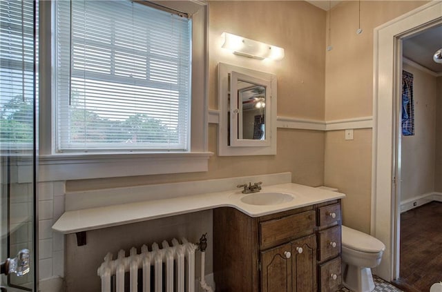 bathroom with radiator heating unit, toilet, wood-type flooring, and vanity