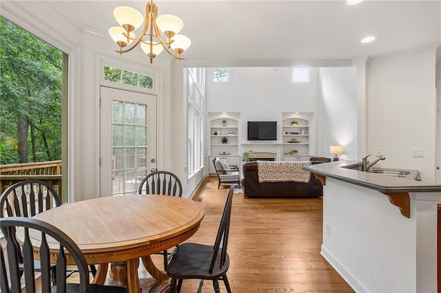 5355 Highland Pine Ln, Mableton, GA 30126 - dining space with crown molding, a chandelier, light wood-type flooring, plenty of natural light, and built in shelves