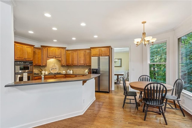 5355 Highland Pine Ln, Mableton, GA 30126 - kitchen featuring stainless steel appliances, brown cabinets, dark countertops, crown molding, and a chandelier