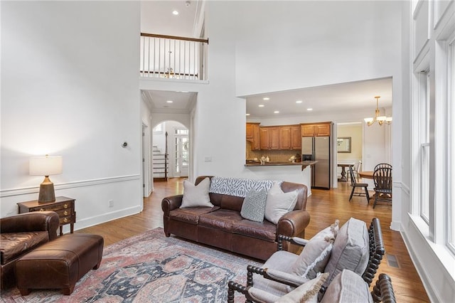 5355 Highland Pine Ln, Mableton, GA 30126 - living room with arched walkways, a towering ceiling, light wood-style floors, a chandelier, and crown molding