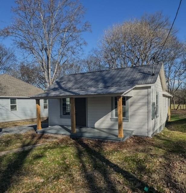 rear view of house featuring a porch and a yard