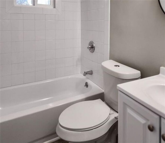 full bathroom featuring tiled shower / bath, vanity, and toilet