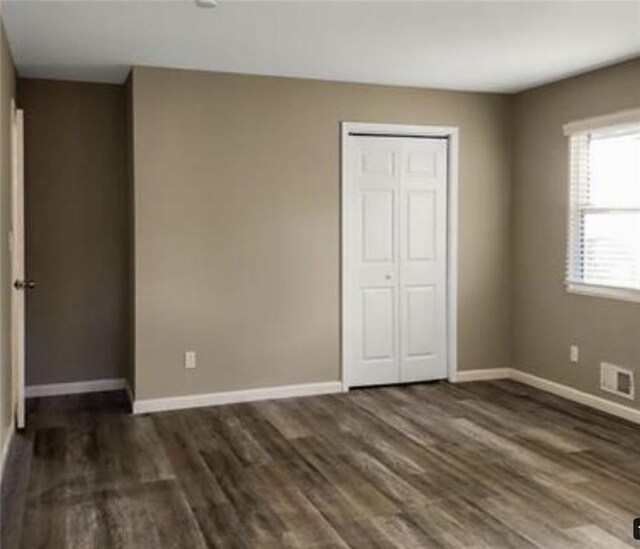 unfurnished bedroom featuring a closet and dark hardwood / wood-style flooring