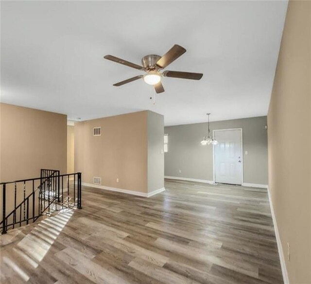 2900 Bradmoor Ct, Decatur, GA 30034 - empty room with baseboards, visible vents, wood finished floors, and ceiling fan with notable chandelier