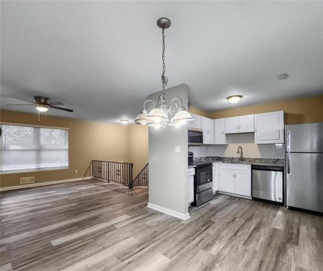 kitchen featuring ceiling fan with notable chandelier, decorative light fixtures, stainless steel appliances, wood-type flooring, and white cabinets