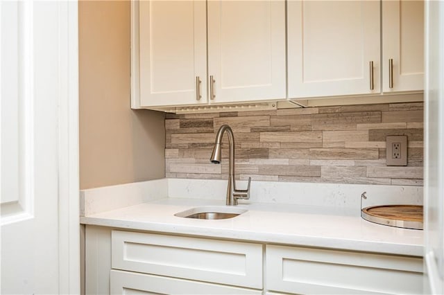 room details with light stone countertops, decorative backsplash, white cabinetry, and sink