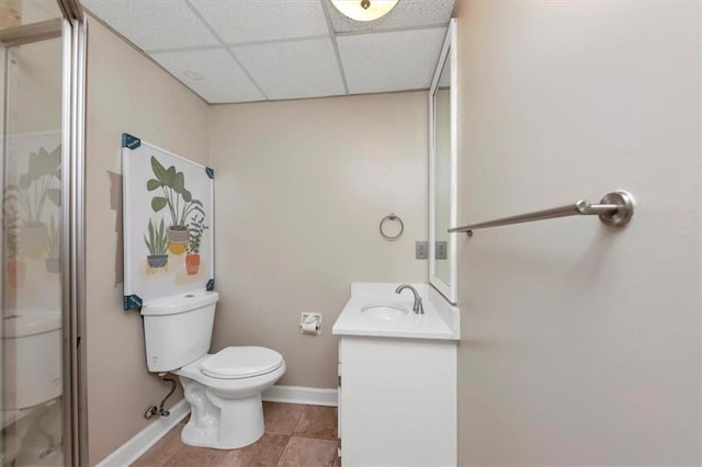 bathroom featuring a drop ceiling, tile patterned floors, toilet, vanity, and a shower with shower door