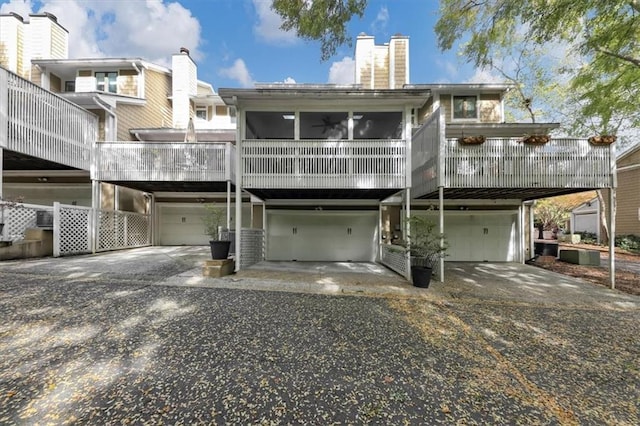 rear view of property featuring a garage and a sunroom