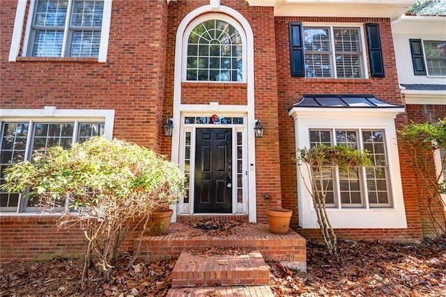 doorway to property with a standing seam roof and brick siding