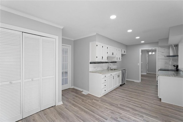 kitchen with stainless steel dishwasher, a sink, light wood-style flooring, and wall chimney exhaust hood