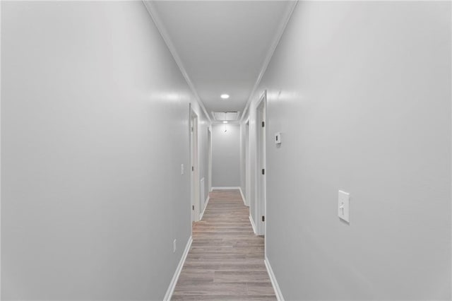 hallway with light wood-style floors, crown molding, and baseboards