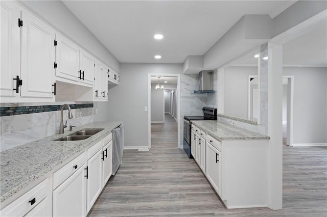 kitchen featuring light stone counters, backsplash, appliances with stainless steel finishes, a sink, and wall chimney exhaust hood