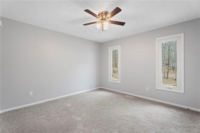 empty room with carpet floors, a ceiling fan, baseboards, and a textured ceiling