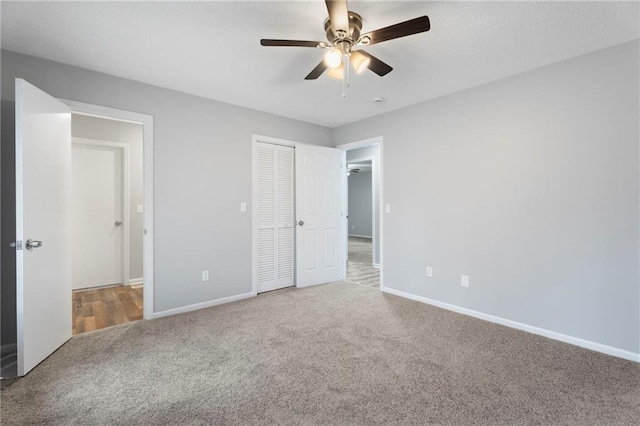 unfurnished bedroom with carpet floors, a closet, a ceiling fan, and baseboards