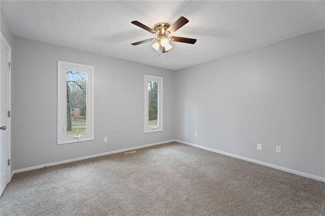 carpeted spare room with ceiling fan, baseboards, and a textured ceiling