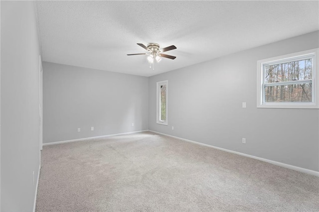 empty room featuring a textured ceiling, carpet floors, ceiling fan, and baseboards