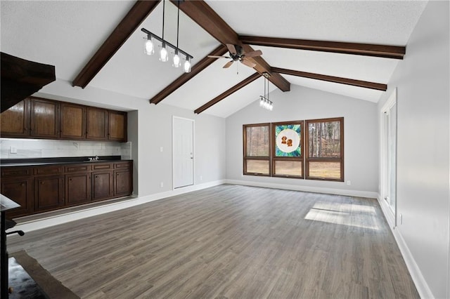 unfurnished living room featuring light wood-type flooring, vaulted ceiling with beams, ceiling fan, and baseboards