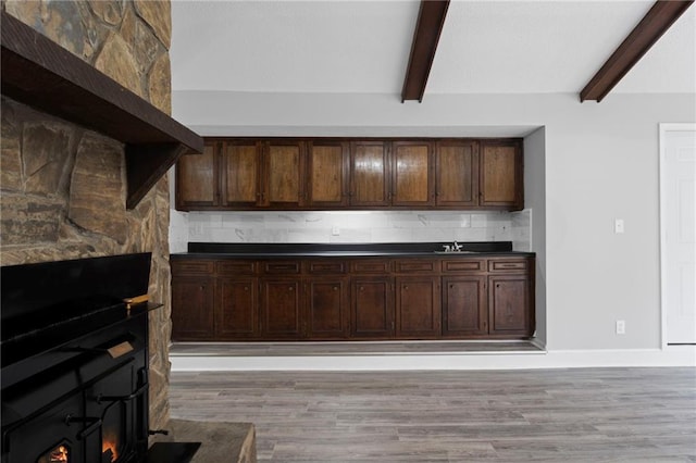 kitchen featuring light wood-style floors, dark countertops, backsplash, and baseboards