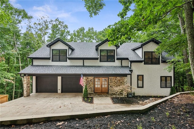 view of front of house with a shingled roof, concrete driveway, stone siding, and an attached garage