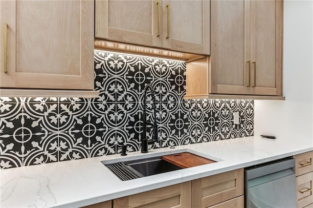 kitchen featuring tasteful backsplash, dishwasher, light stone counters, light brown cabinetry, and a sink