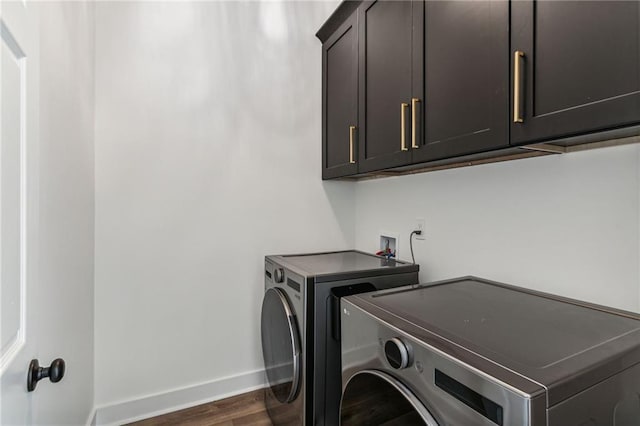 laundry room with cabinet space, baseboards, separate washer and dryer, and dark wood-type flooring