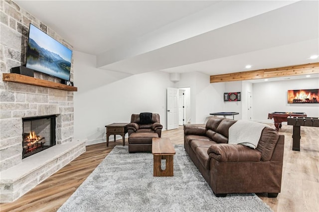 living area featuring beam ceiling, recessed lighting, pool table, a stone fireplace, and wood finished floors