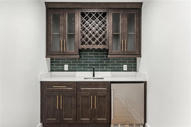 bar with wet bar, a sink, decorative backsplash, and stainless steel refrigerator