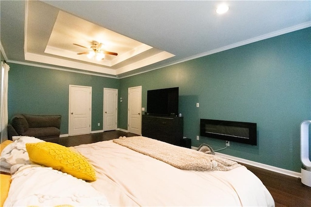 bedroom featuring a tray ceiling, crown molding, dark hardwood / wood-style floors, and ceiling fan