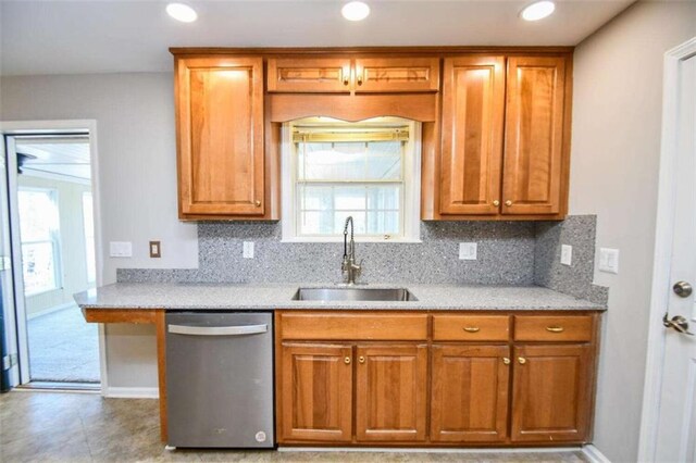 kitchen featuring light stone countertops, decorative light fixtures, sink, backsplash, and stainless steel dishwasher