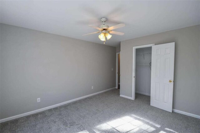 unfurnished bedroom featuring a spacious closet, ceiling fan, a closet, and light colored carpet