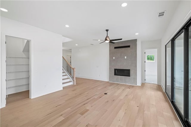 unfurnished living room featuring ceiling fan, built in features, a fireplace, and light hardwood / wood-style flooring