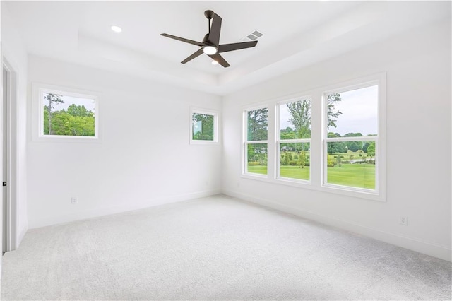 carpeted spare room with ceiling fan and a tray ceiling