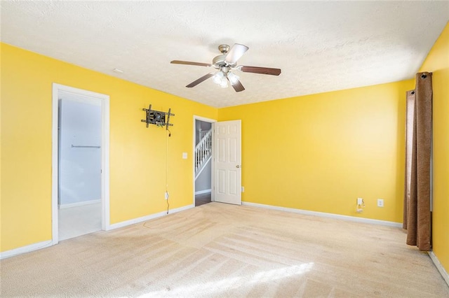 spare room featuring ceiling fan, light carpet, and a textured ceiling