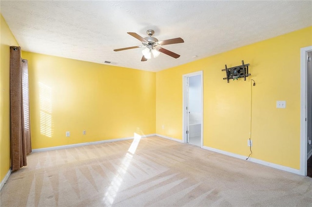 spare room with ceiling fan, light colored carpet, and a textured ceiling