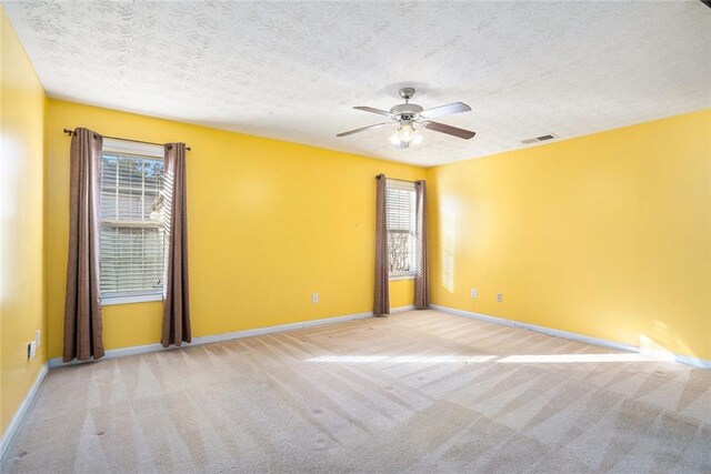 spare room with a textured ceiling, ceiling fan, and light carpet