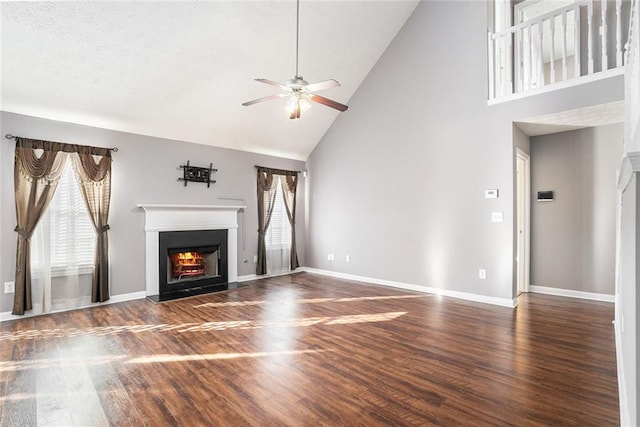 unfurnished living room with dark hardwood / wood-style flooring, plenty of natural light, high vaulted ceiling, and ceiling fan