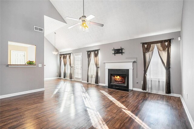 unfurnished living room featuring a textured ceiling, ceiling fan, dark hardwood / wood-style flooring, and vaulted ceiling