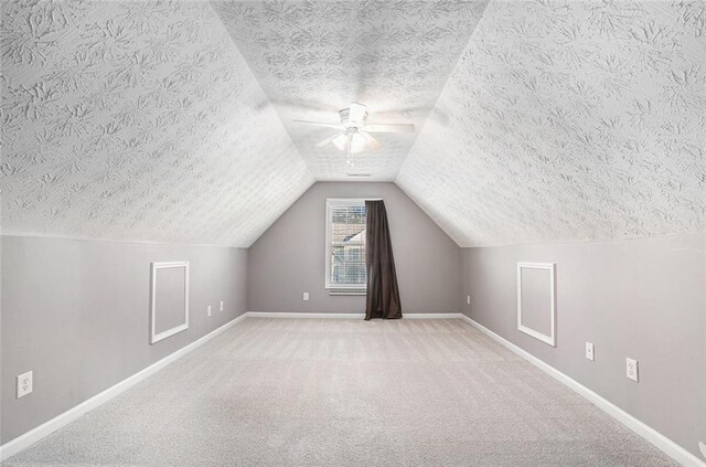 additional living space with a textured ceiling, light colored carpet, vaulted ceiling, and ceiling fan