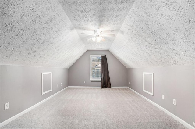 additional living space with ceiling fan, lofted ceiling, light carpet, and a textured ceiling