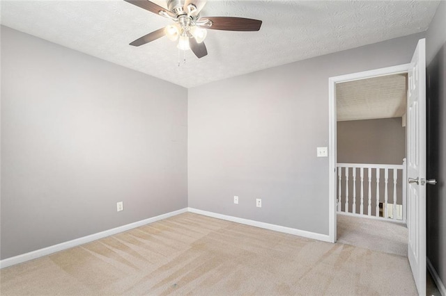 empty room with ceiling fan, light colored carpet, and a textured ceiling