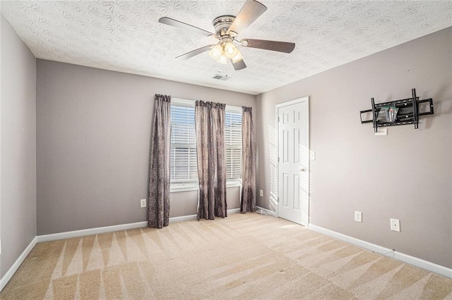 unfurnished room with light colored carpet, a textured ceiling, and ceiling fan