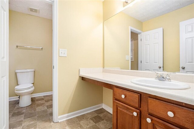 bathroom featuring vanity, toilet, and a textured ceiling