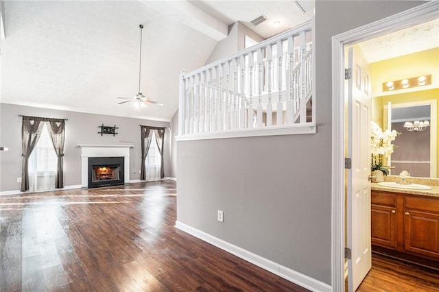 living room with hardwood / wood-style floors, vaulted ceiling with beams, ceiling fan, and sink