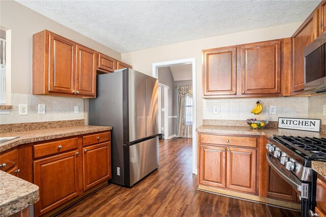 kitchen featuring a textured ceiling, tasteful backsplash, stainless steel appliances, and dark hardwood / wood-style floors