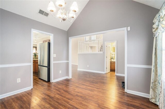 empty room with a chandelier, vaulted ceiling, and dark wood-type flooring