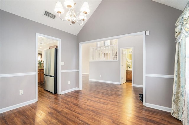 spare room with vaulted ceiling, dark hardwood / wood-style floors, and an inviting chandelier